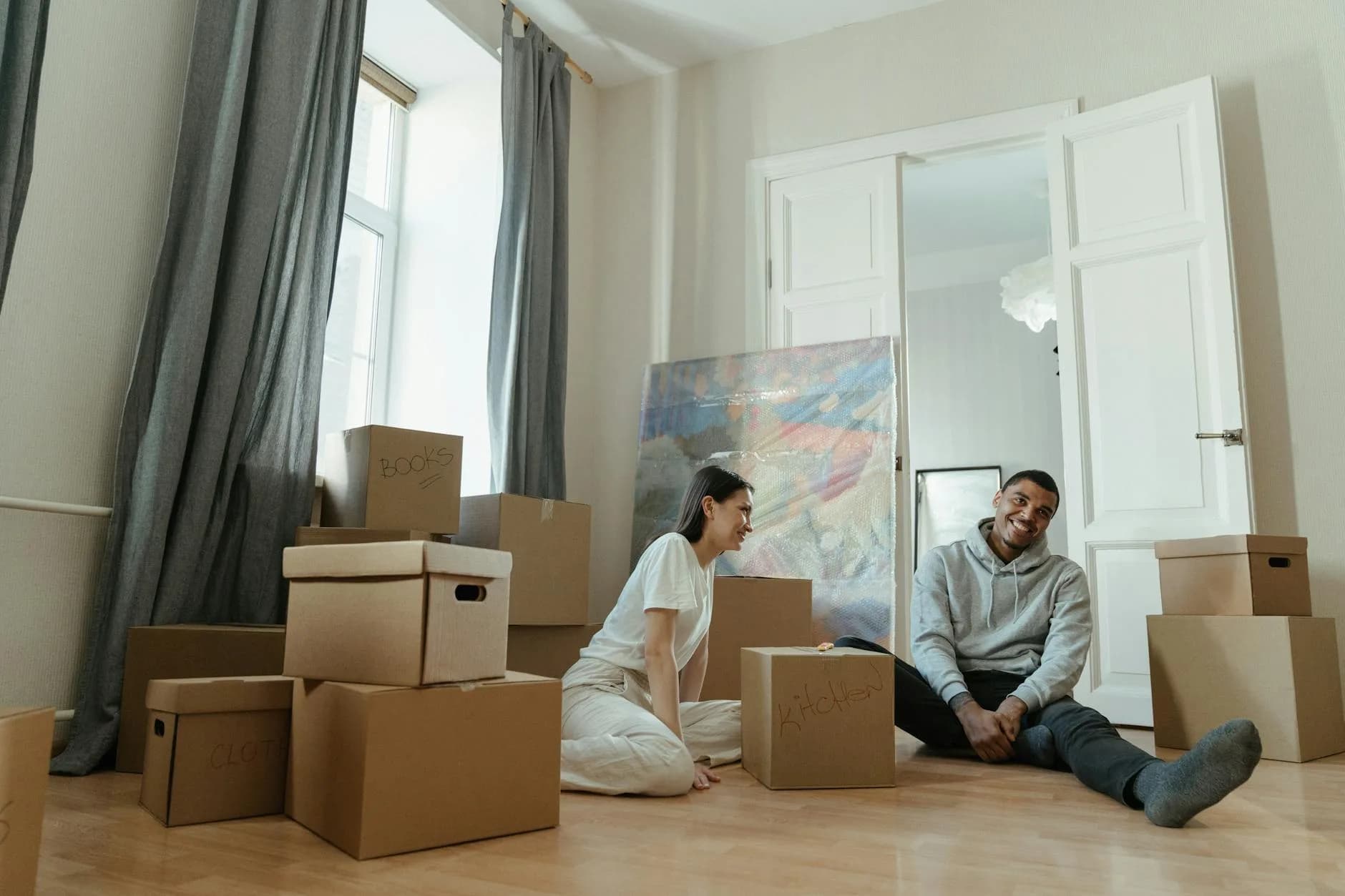 Cartons de déménagement empilés dans un appartement vide près d'une grande fenêtre